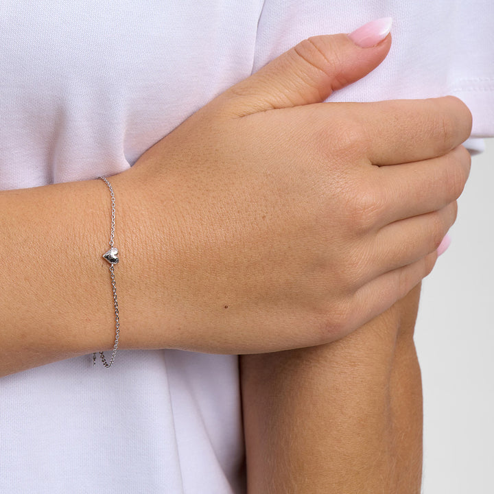 Sweet Diamonds Armbånd sølv med lille hjerte, båret på håndled på hvid trøje. Model7150357_1M