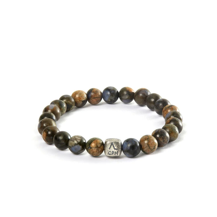 Alexander Lynggaard Bracelet Glaucophane 8mm shows a bracelet of round, brown and blue stones with a metal bead, Model c01180-001