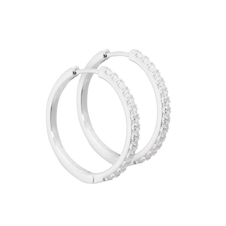 Aqua Dulce Darling Silver Hoop Earrings 25mm shows a close-up image of two silver earrings with clear stone details. Model 3832-3832-1