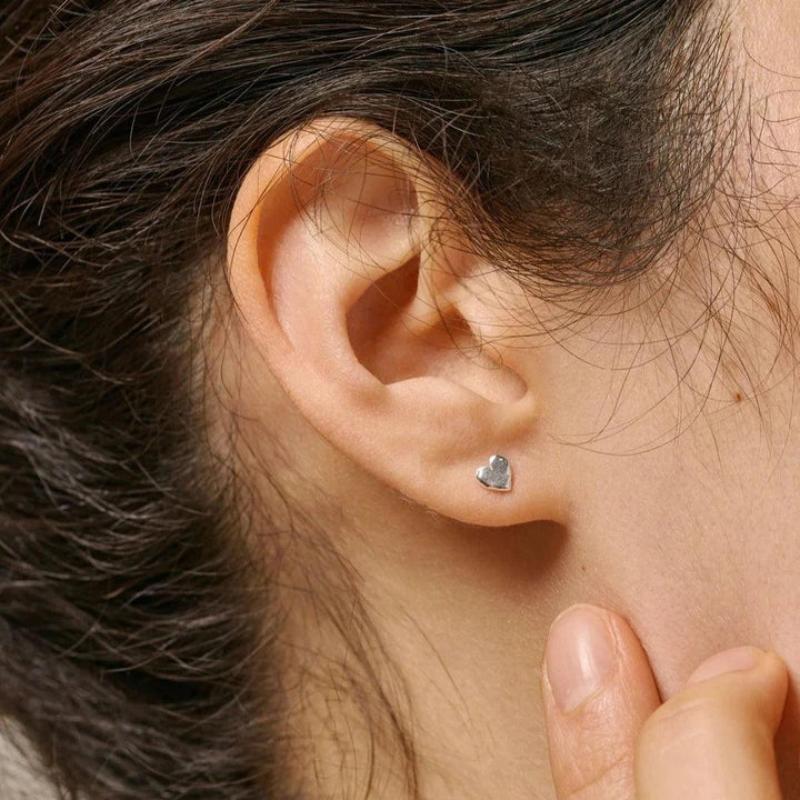 Enamel Heart Studs are shown as silver-colored heart earrings in the model's ear, elegant and minimalistic. Model E373SM-E373SM-2