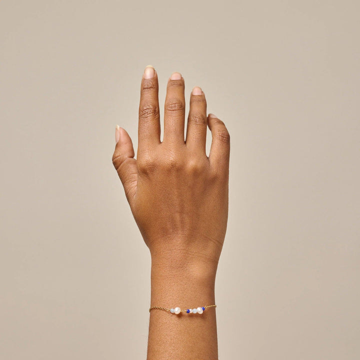Enamel Sofia Bracelet Marine is shown worn on the wrist, golden chain with white and blue pearls. Model b136g-marine