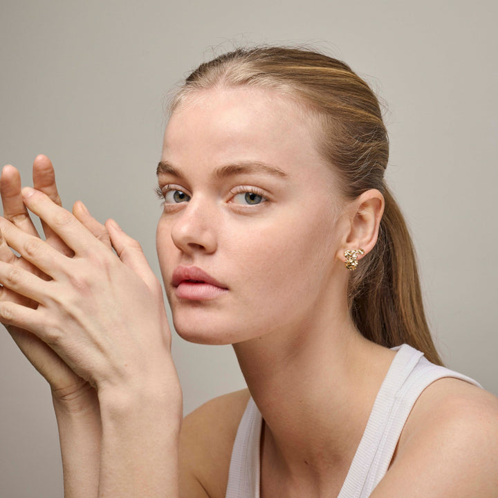 Enamel Sunshine Field Stud e417g is shown worn by a woman, golden earrings in an organic shape. Model e417g-2