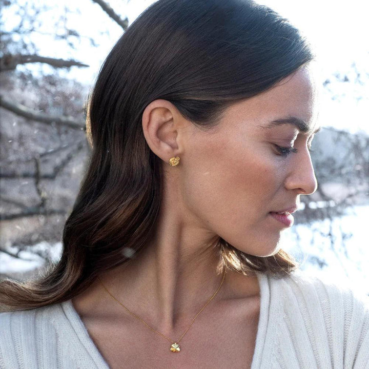 Flora Danica Fir clover necklace 18kt gold shown worn by woman in nature with Model flc-ne-18k-g-2.