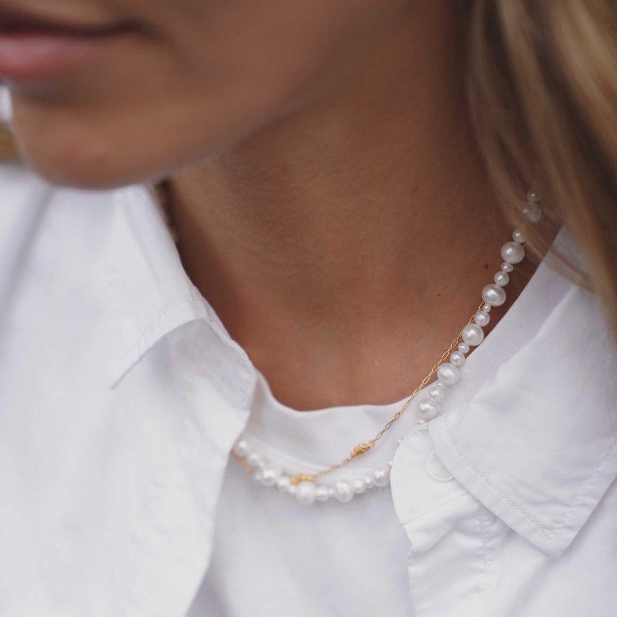 Hultquist Copenhagen Josephine Perle Necklace with white freshwater pearls and golden chain worn over white shirt. Model S08558G-1