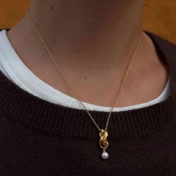 Hultquist Tiril Necklace Gold plated seen on model, elegant gold chain with braided pendant and pearl. Model S08646G-2.