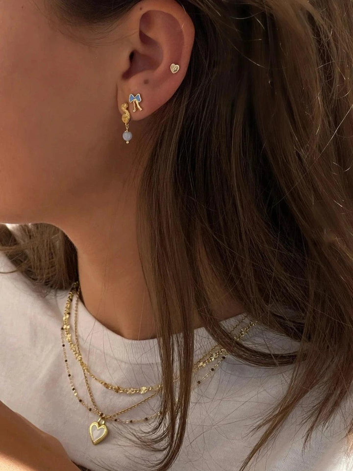 Jeberg Petite Bow Blue Stud Earrings Shown On Ear, Blue Bow in Gilded Design, Model 52810-2