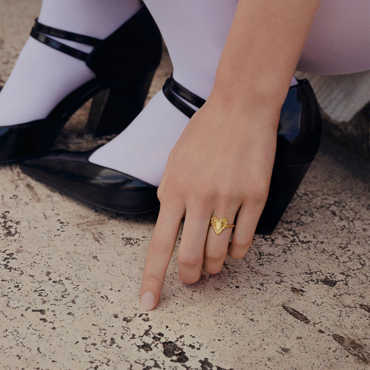 The moonstone Abra gold-plated heart ring on one hand shows the details of the golden design. Model 4876a-001