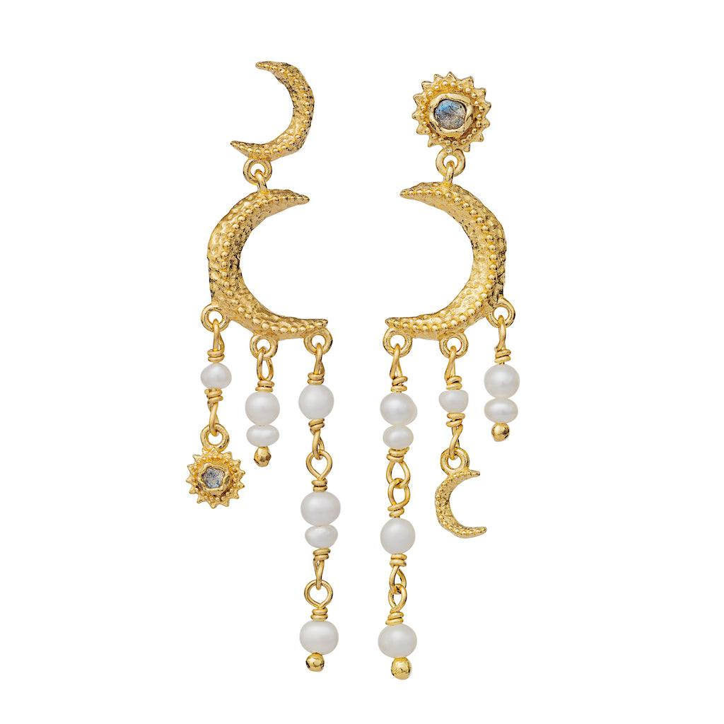 Maanesten Astrea Earrings 18 kt gold-plated appear as two golden, crescent-shaped earrings with hanging pearls and details. Model 9718a-9718a-1