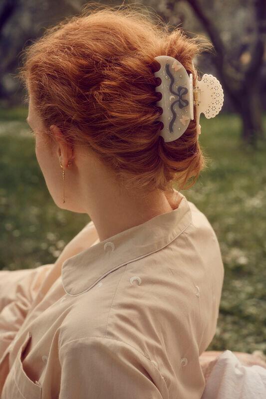 maanesten-desiree-hair-claw-off-white is seen in the woman's styled red hair, in a sunny outdoor environment. Model 3973-one size