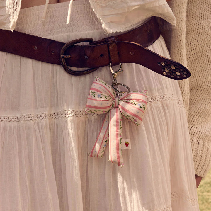maanesten-fabric-bow-key ring-summer-stripes-peach pod-shaped key ring in pink and white cotton stripes, worn on a leather belt. Model 4112-2.