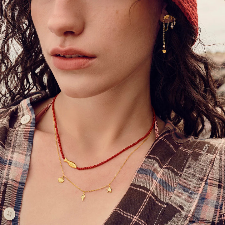 maanesten-iluka-necklace-gilded with golden charms and red beads, worn by woman, Model 2818a-2