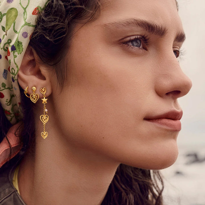 maanesten-irena gold-plated-heart earrings shown on ear with multiple gold-plated heart pendants. Model 10096a