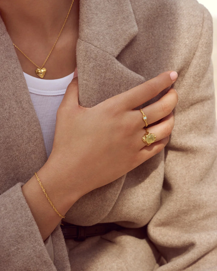 Moonstone Lisa gold plated ring is shown on a hand with beige coat, gold color, unique texture. Model 4745a-001-2.