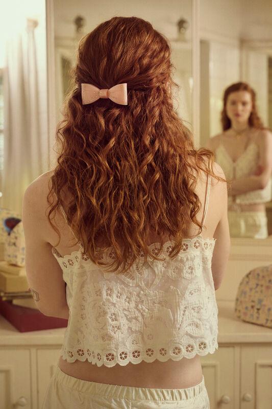 Ribin hair clip blush in pink adorns wavy hair, worn by woman in front of mirror. Model 3979