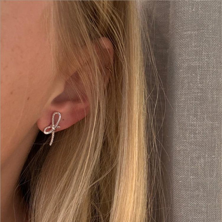 Mads Z Miss Butterfly bow earrings in silver with white topaz appear on ear. Model 2116003-2