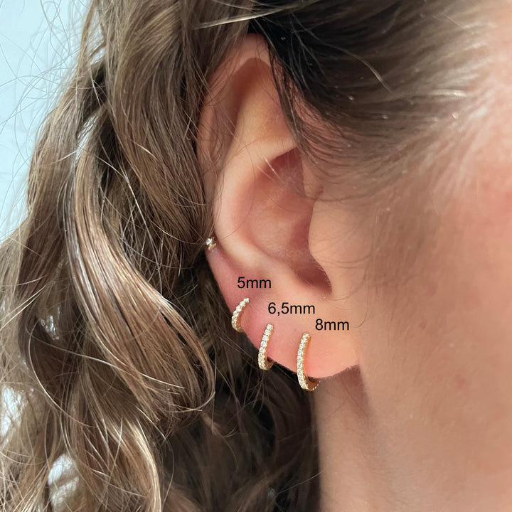 Maria Tash Diamond Eternity Hoop 8mm 18kt appears on the ear, elegant gold color with diamonds. Model xetd-yg-d8-2