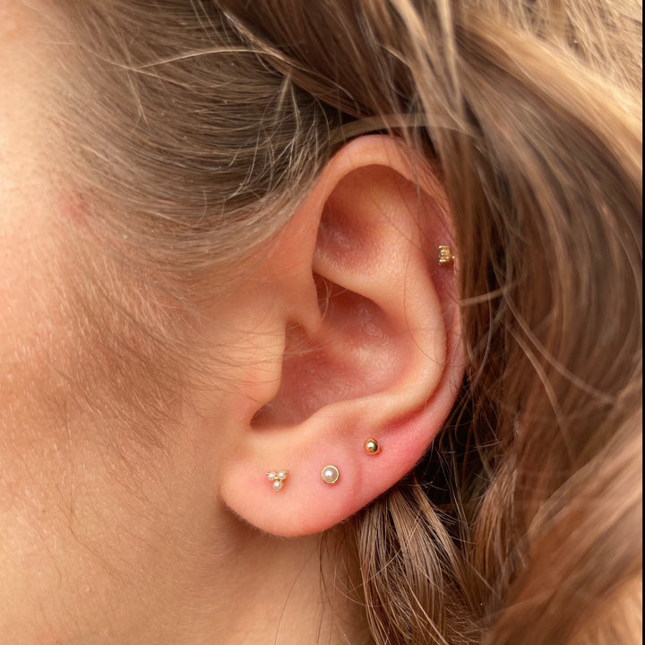 Maria Tash Natural Pearl Threaded Stud Earring 14kt is displayed in an ear, discreet freshwater pearl on gold. Model xpe-yg-w2-001-2.
