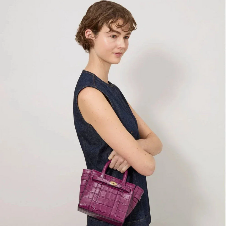 Mulberry Micro Zipped Bayswater Orchid Bloom Shiny Small Croc is shown carried in the hand of a woman. Model RL8691641J512