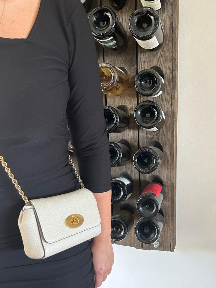 Mulberry Mini Lily Heavy Grain Chalk, worn crossbody on woman in black clothing, in front of wine rack. Model rl7944736w160-2