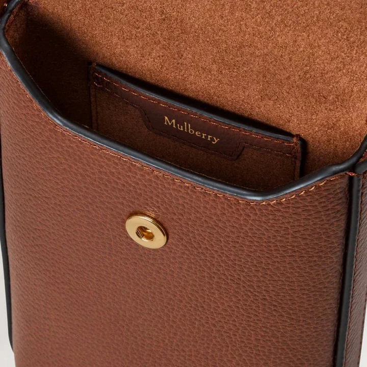 Mulberry Press Stud Phone Pouch oak showing close-up of brown leather surface and gold colored push button, Model RL9007552G110