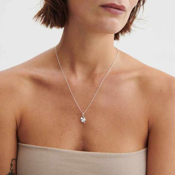 Pernille Corydon Clover Pendant, a gold-plated four-leaf clover pendant is worn around the model's neck. Model P-964-GP-2