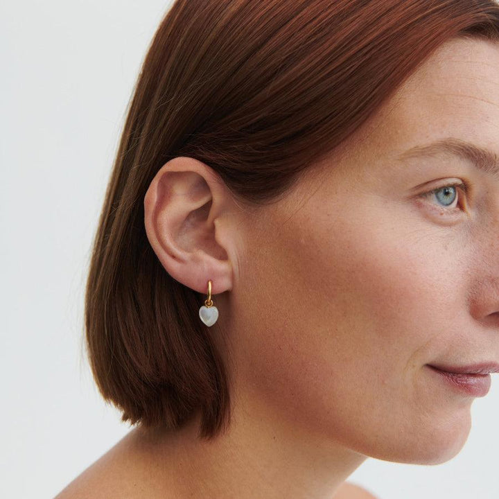 Pernille Corydon Ocean Heart Gold Plated Huggies appear on the ear, heart shaped pendant in gold. Model E-387-GP-2