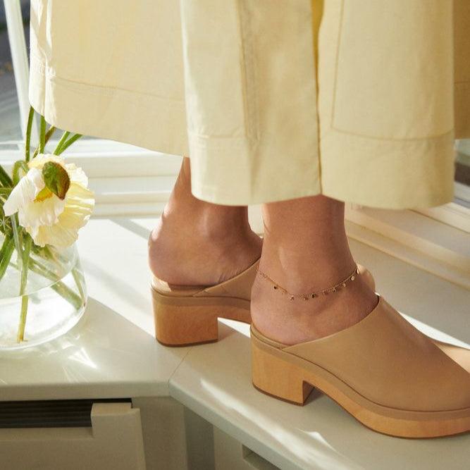 Pernille Corydon Sheen Gold Plated Anklet worn on the ankle, seen in sunlight with beige shoes. Model A-315-GP-1