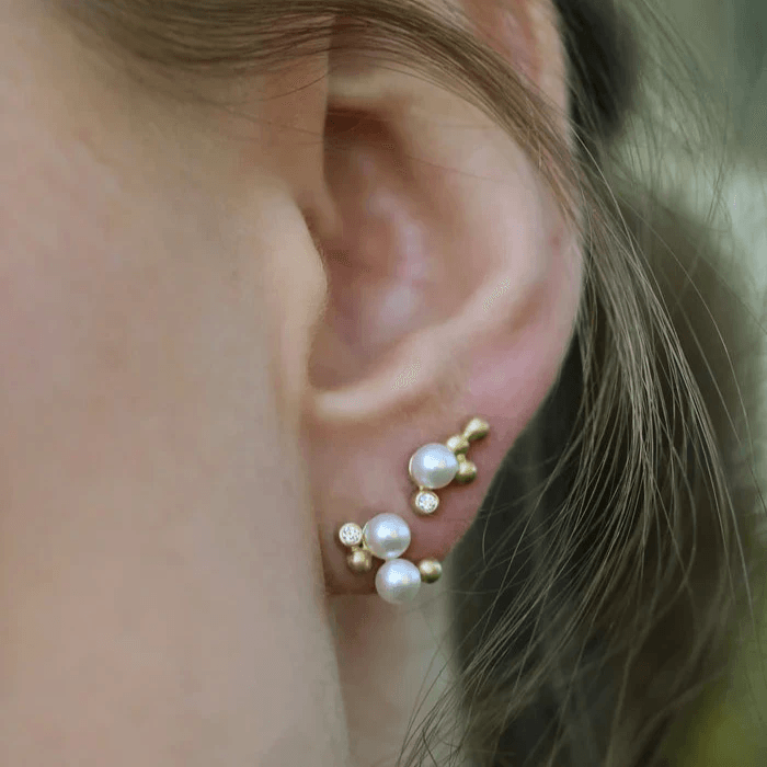 RO Copenhagen Orbit Dot Pearl earring left shown on ear with white pearls and golden details, Model E118Y105-2.