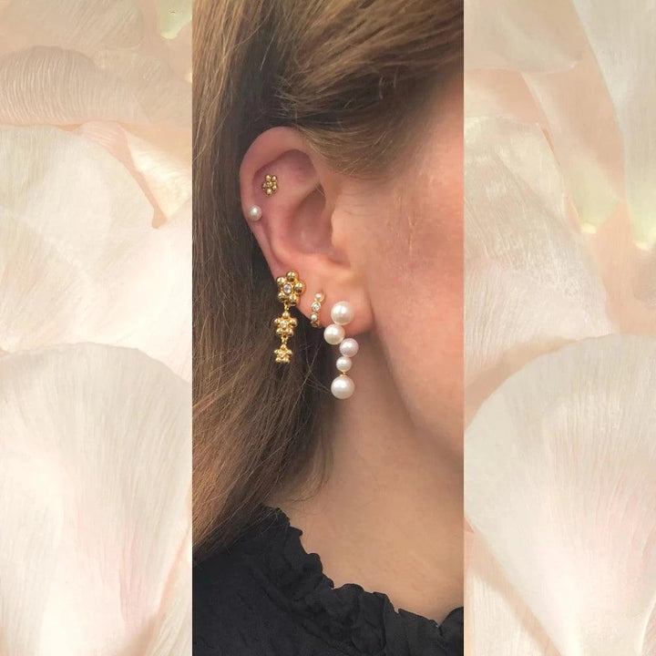 Ellie Huggie PearlWhite appears on the ear with pearls and golden details, elegant and modern. Model FW2308-2.