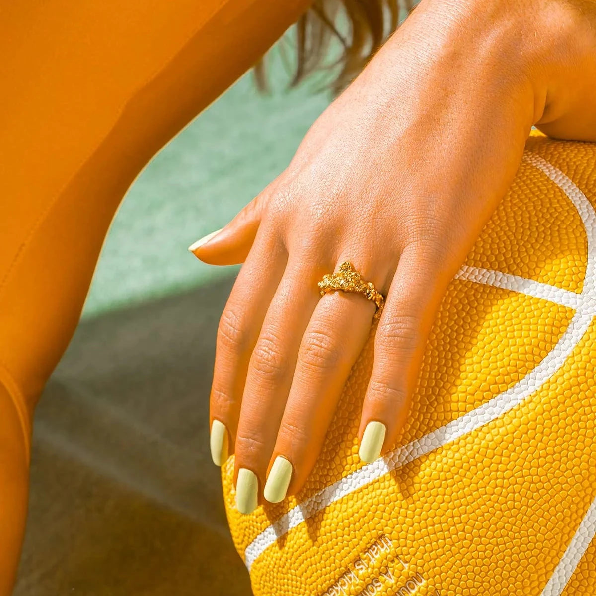 vincent glimmering haze gold-plated ring appears on a woman's hand against orange ball, Model VJ185-URG-001