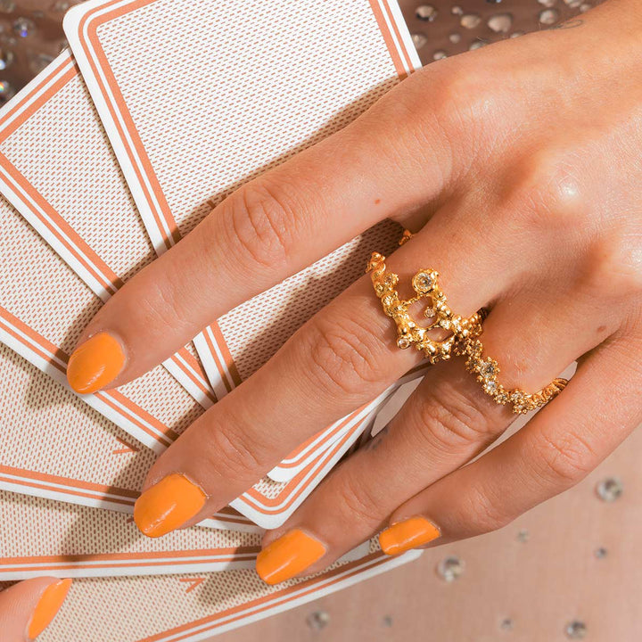 Vincent Starlit Ring Gilt shows a golden, textured ring on a hand with orange nails, Model VJ217-URG-001-2.