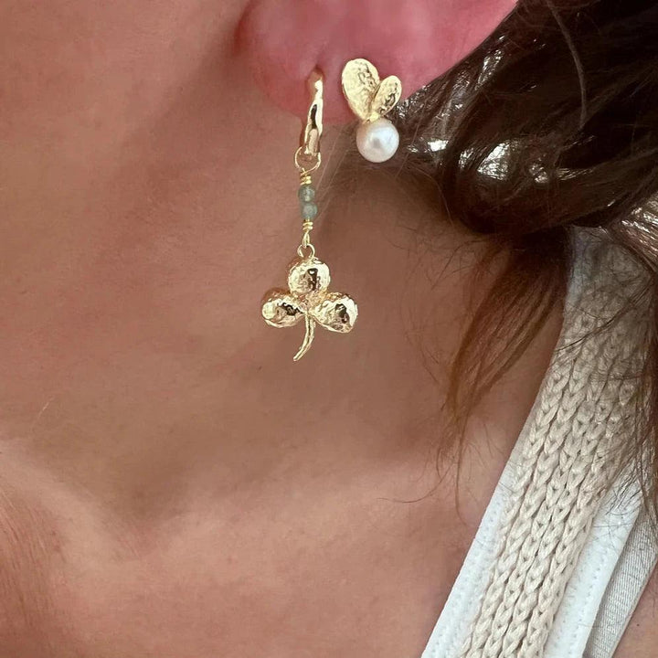Wioga Madison earrings with trefoil, gold-coloured with pearl detail, seen on ear. Model E-8905-gp.