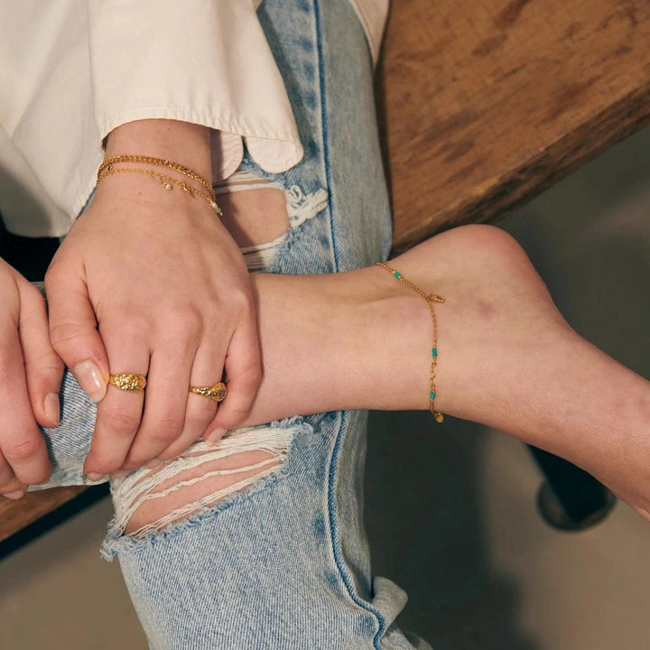Wioga Octavia ankle chain gold plated with turquoise shown on ankle, casual style. Model A-8638-GP-1.