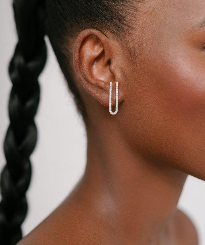herieth-paul-x-polar-jewelry-zanzibar-solve-ring. Elegant silver earring with U-shape and small stones on a woman's ear. Model Zan-st-sl-wz-00509-2.