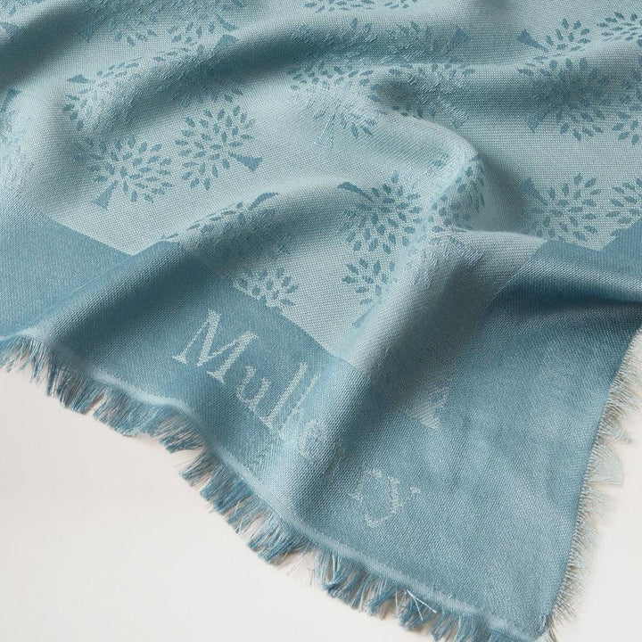 Mulberry Tree Square Silk Organic Cotton Cloud shows a blue scarf with a discreet tree pattern. Model vs4639709d140