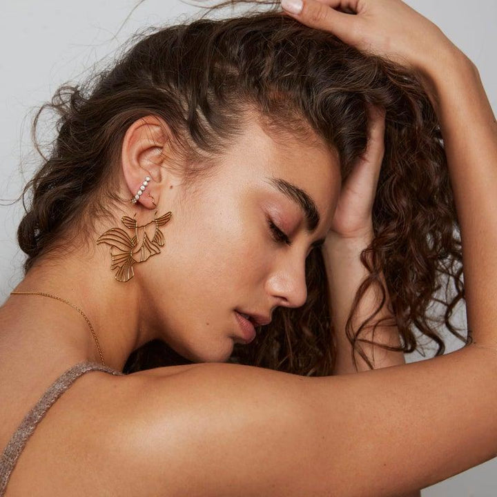 Polar Jewelry Gold Plated Koi Hoops appear on woman with wavy hair, elegant gold colored earrings. Model Koi-HP-GD-00101-2