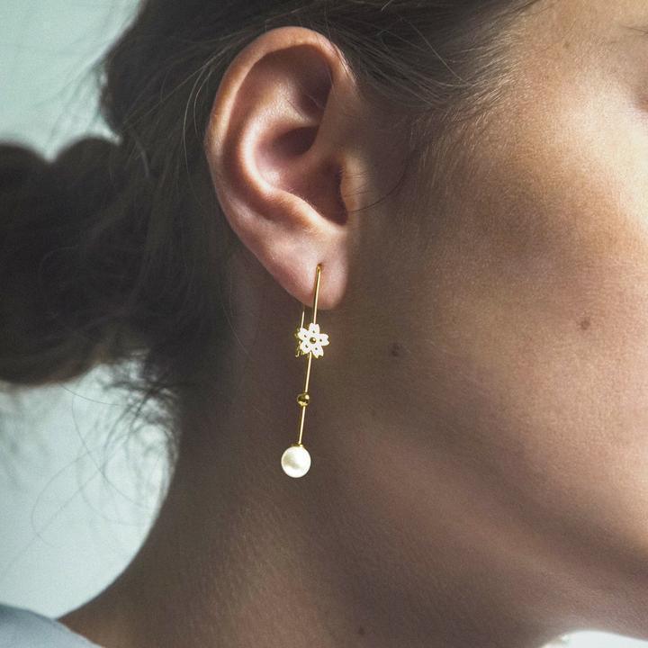 Polar Jewelry Sakura Hanging Pearl gold-plated earring is seen on ear, with gold flower and pearl. Model SAK-EH-GD-WP-00120