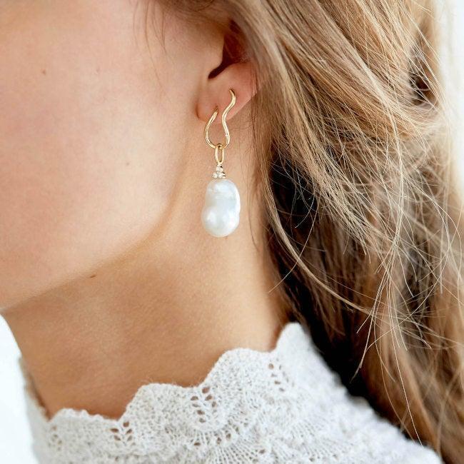 RO Copenhagen 18kt Enjoy Baroque Pearl Pendant shown on ear, beautiful baroque pearl in golden suspension. Model 106699-2