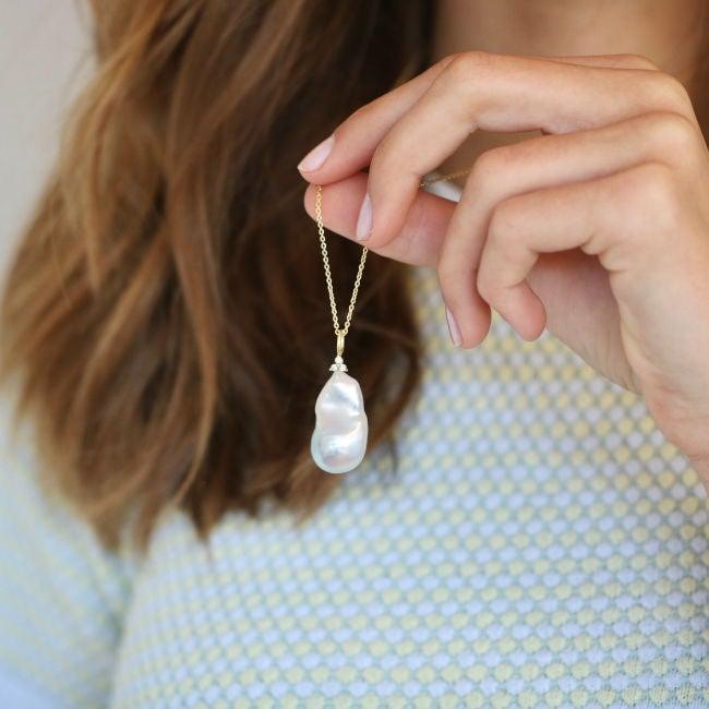 ro copenhagen 18kt joy baroque pearl pendant diamonds displayed in hand against patterned jersey. Model 108637-2